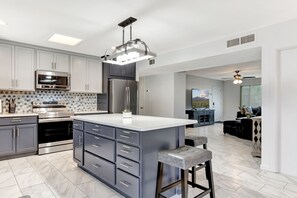 Una cocina moderna con armarios grises, electrodomésticos de acero inoxidable y una isla central.