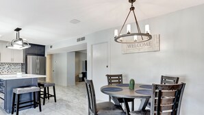 A modern kitchen with a central island, dark wooden chairs, and a chandelier. - Casa Azul - Pool, ASU, Mill Ave, Sky Harbor, Old Town (Tempe)