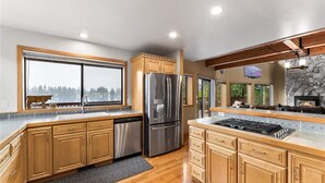A modern kitchen with wooden cabinets, stainless steel appliances, and a stone accent wall.