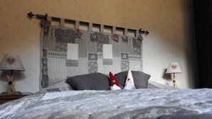 Ein ordentlich bezogenes Bett mit gestepptem Kopfteil, zwei Nachttischlampen und drei Kissen.
