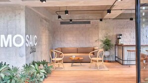 A modern interior with a sofa, chairs, a small table, and a coffee machine. - PRIME LOCATION / Mosaic Studios Barranquilla P-1 (Barranquilla)
