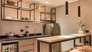 A modern kitchen with a wooden table, built-in appliances, and a hanging light fixture. - PRIME LOCATION / Mosaic Studios Barranquilla P-1 (Barranquilla)