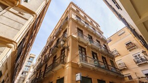 Un immeuble à plusieurs étages, doté de balcons, de grandes fenêtres et d’une enseigne indiquant qu’un commerce est situé au rez-de-chaussée.