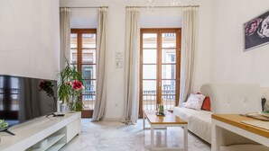 Un salon moderne doté d’un téléviseur à écran plat, d’une table basse, d’un canapé et offrant une vue sur le balcon.