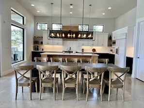 A modern kitchen with a central island, white cabinetry, and a large window.