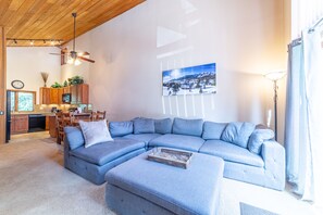 Ein Wohnzimmer mit Ecksofa, einer Essecke mit Holzausbau und einer Küche mit Mikrowelle.