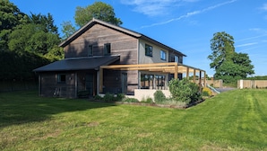 A modern two-story house with a covered patio, a small garden, and a slide. - Unique, Spacious, Self-Built Eco House with Huge Garden and Movie Room (Andover)