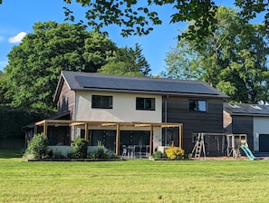 A modern two-story house with a covered patio and solar panels on the roof.