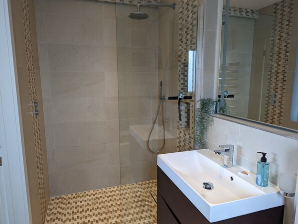 A bathroom with a shower, a sink, and a mirror. - Unique, Spacious, Self-Built Eco House with Huge Garden and Movie Room (Andover)