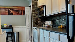 A kitchen with white cabinets, a black refrigerator, and a stone backsplash.