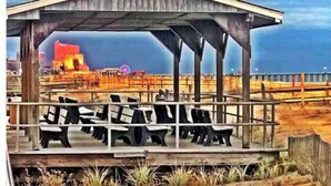 A wooden structure with a roof, seating area, and a view of the beach and cityscape.