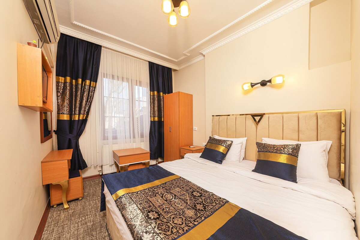 A hotel room with a bed, bedside tables, a wardrobe, and a desk.