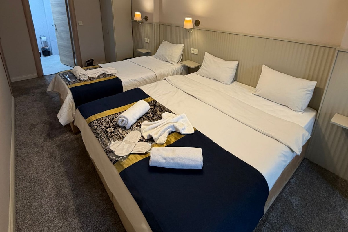 A hotel room with two beds, a wardrobe, a desk, and a bathroom visible through an open door.
