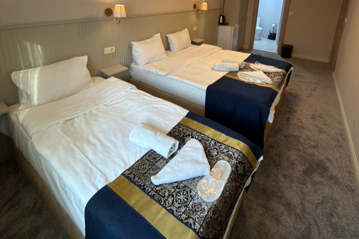 A hotel room with three beds, each with a different bedspread, and a bathroom visible through an open door.