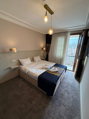 Een hotelkamer met een groot bed, twee bedlampjes, uitzicht door het raam en een plafondlamp.