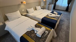 A hotel room with two beds, a ceiling light fixture, and a window with curtains.