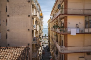 A narrow street flanked by multi-story buildings with balconies, a tiled roof, and a view of the sea. - B&B Arco dei Pinto (Salerno)