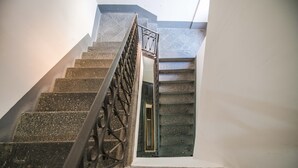 Una escalera con barandilla de metal y vista a una habitación por una ventana.