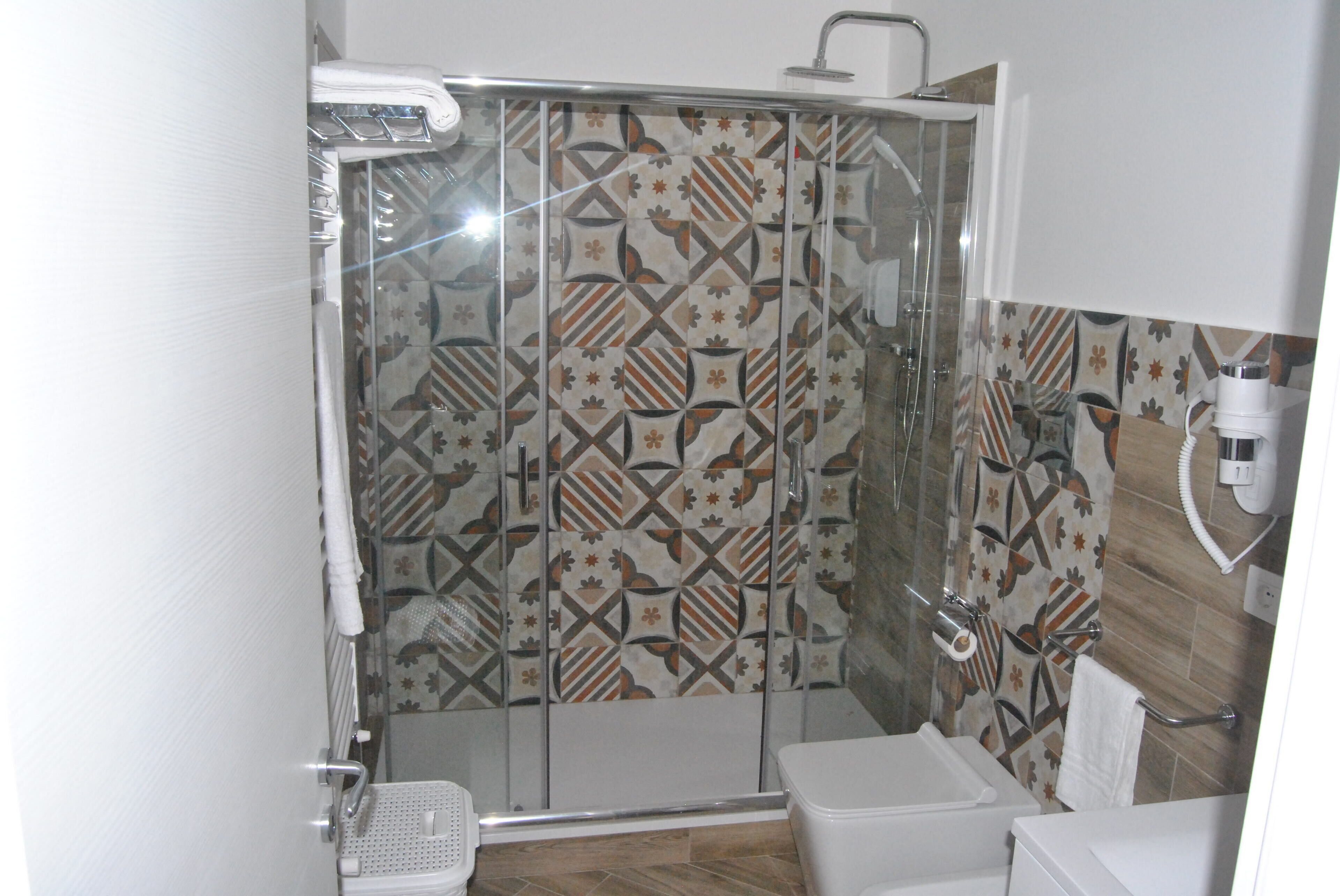 Une douche avec une porte en verre, des toilettes et un lavabo.