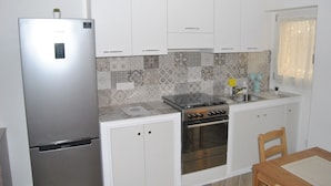 A compact kitchen with white cabinets, a stainless steel refrigerator, a gas stove, and a built-in oven. - Agrigento Centre - 1-bed Apartment - Sleeps 4 (Agrigento)