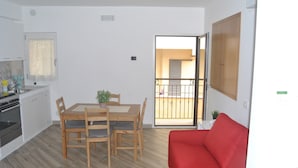 A compact living space with a dining area, kitchenette, and a red sofa. - Agrigento Centre - 1-bed Apartment - Sleeps 4 (Agrigento)