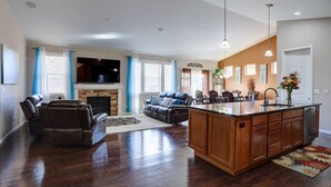 A spacious living room with a fireplace, a sofa, a recliner, and a kitchen island with a sink. - 4 Bed/3 Bath, Sleeps 12! 20 min DIA, Pets-Large yard; Great for Families! (Commerce City)