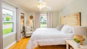 Ein Schlafzimmer mit Bett, Stuhl, Deckenventilator und Blick ins Freie.