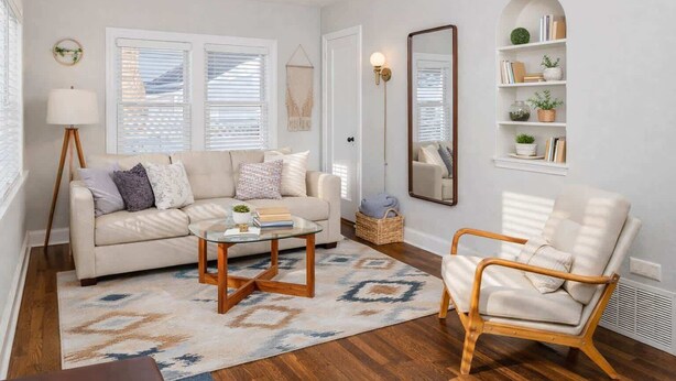 A living room with a beige sofa, a glass coffee table, a wicker basket, and a wooden chair.