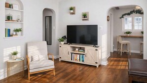 A living room with a TV, bookshelves, and a wooden floor.