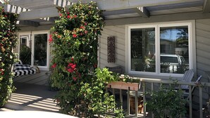 A house with a covered porch, a swing chair, a potted plant, and a window with blinds. -  Gorgeous Chalet in historic San Diego's premier neighborhood- Mission Hills! (San Diego)