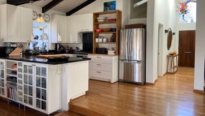 A modern kitchen with white cabinetry, a large island, stainless steel appliances, and wooden flooring. -  Gorgeous Chalet in historic San Diego's premier neighborhood- Mission Hills! (San Diego)