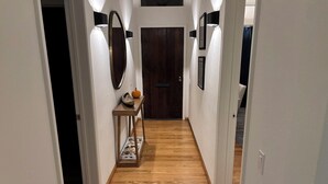 A hallway with wooden flooring, a small table with a decorative item, and a door at the end. -  Gorgeous Chalet in historic San Diego's premier neighborhood- Mission Hills! (San Diego)