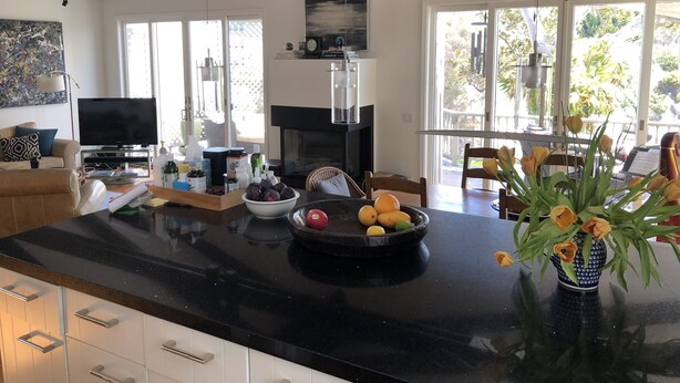 A modern kitchen with a black countertop, a bowl of fruit, and a vase of flowers. -  Gorgeous Chalet in historic San Diego's premier neighborhood- Mission Hills! (San Diego)