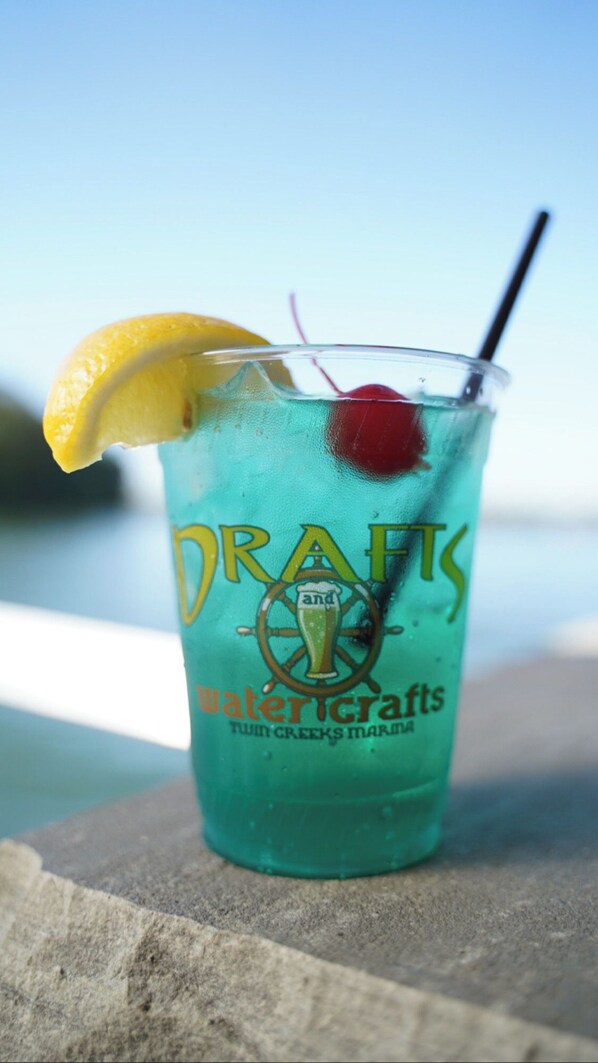 Un vaso de cóctel azul con una cuña de lim ón y una cereza, con la leyenda 'DRAFTS Watercrafts Twin Creeks Marina'.