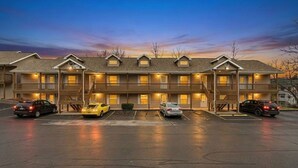 Un motel con varios pisos, un estacionamiento y coches aparcados al frente.
