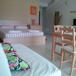 Une chambre à coucher avec un lit, une chaise en bois, un canapé et une petite table.