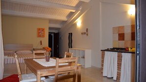 Un espacio habitable compacto con comedor, kitchenette y cama con ropa de cama a rayas.