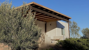 Une maison moderne avec un toit plat, des fondations en pierre et une pergola en bois.
