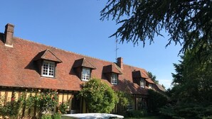 A traditional brick house with a well-maintained garden and a covered table in the foreground. - Normandy vacation home with swimming pool 12km from Verneuil sur avre (Mesnils sur Iton)