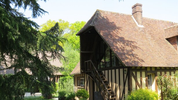 A traditional timber-framed house with a steeply pitched roof, a visible staircase, and a well-maintained garden with various plants and a pathway. - Normandy vacation home with swimming pool 12km from Verneuil sur avre (Mesnils sur Iton)