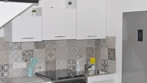 Een moderne keuken met witte kastjes, een roestvrijstalen spoelbak en betegelde spatwand.