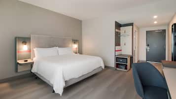A hotel room with a bed, bedside tables, a desk, and a chair.