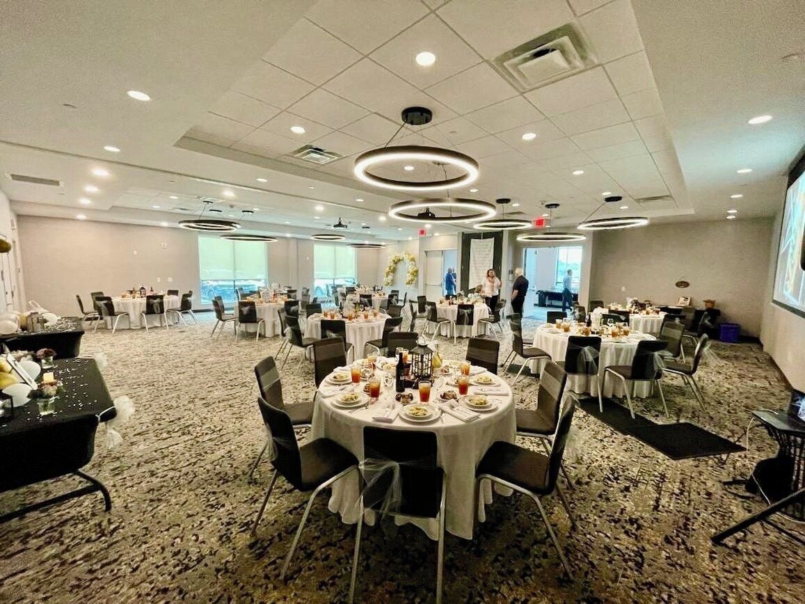 A conference room with round tables, white tablecloths, and chairs.