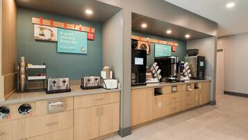 A modern kitchen area with a coffee machine, toaster, and refrigerator.