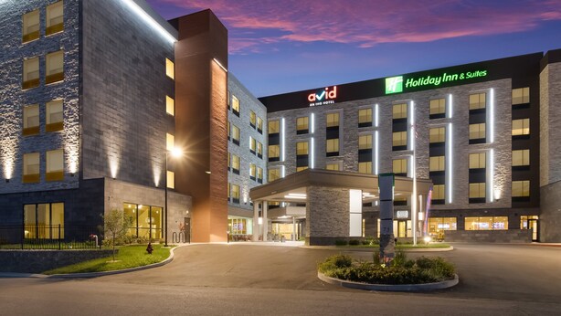 Edificio de Holiday Inn & Suites con un diseño moderno, que presenta un llamativo letrero 'avid' y una entrada bien iluminada.