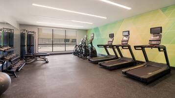 A gym with treadmills, weight machines, and exercise balls.