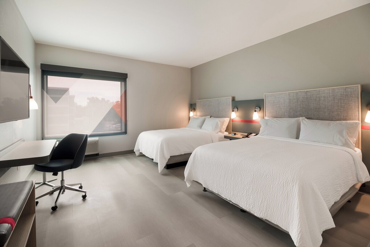 Une chambre d’hôtel avec deux lits, un bureau et une chaise.