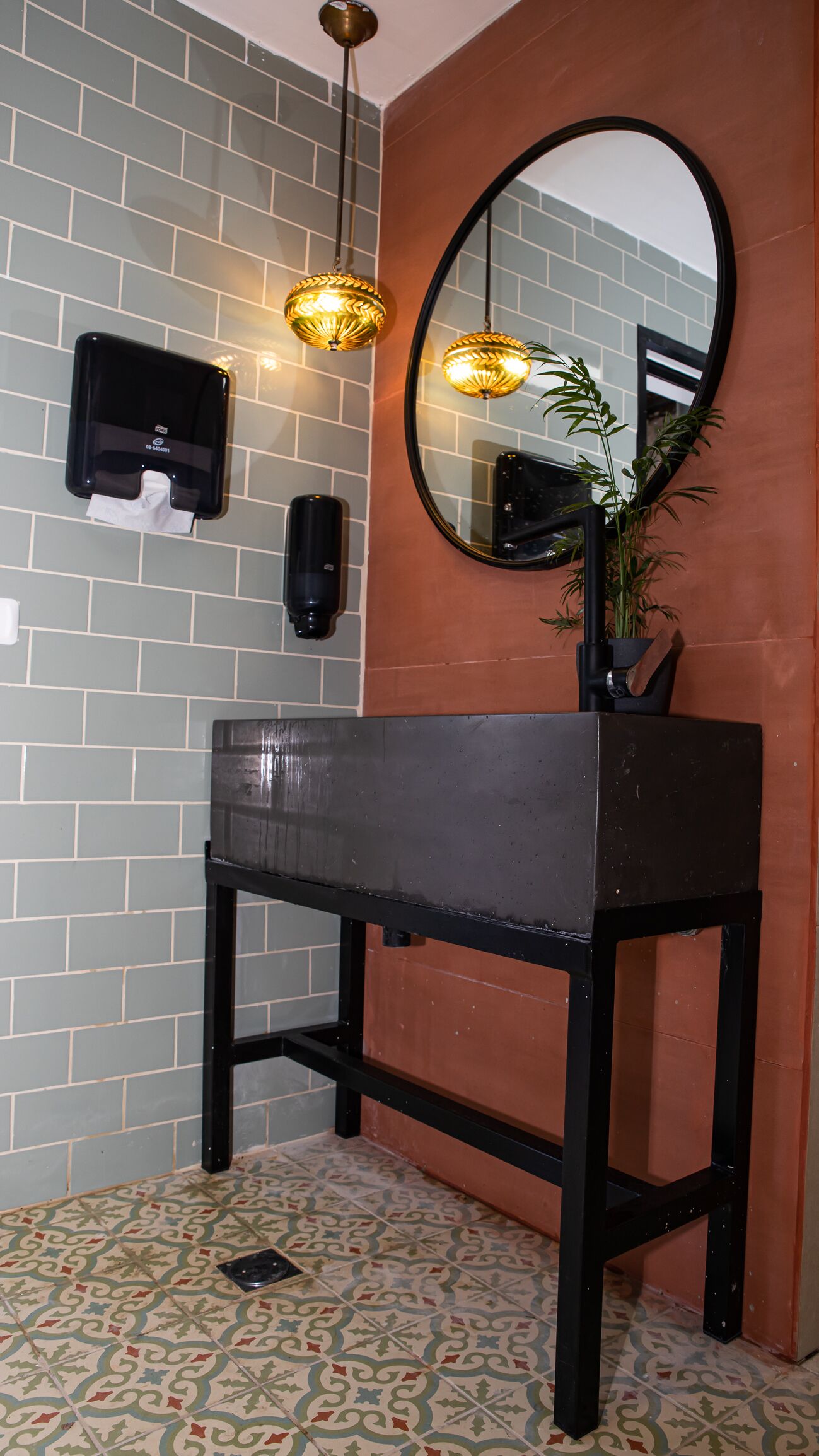 A bathroom with a black sink, a mirror, and two wall-mounted light fixtures.