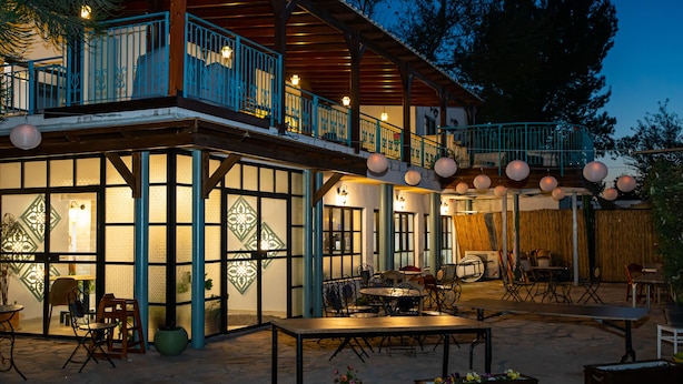Een gebouw met twee verdiepingen, een overdekt terras, grote ramen en decoratieve lantaarns.