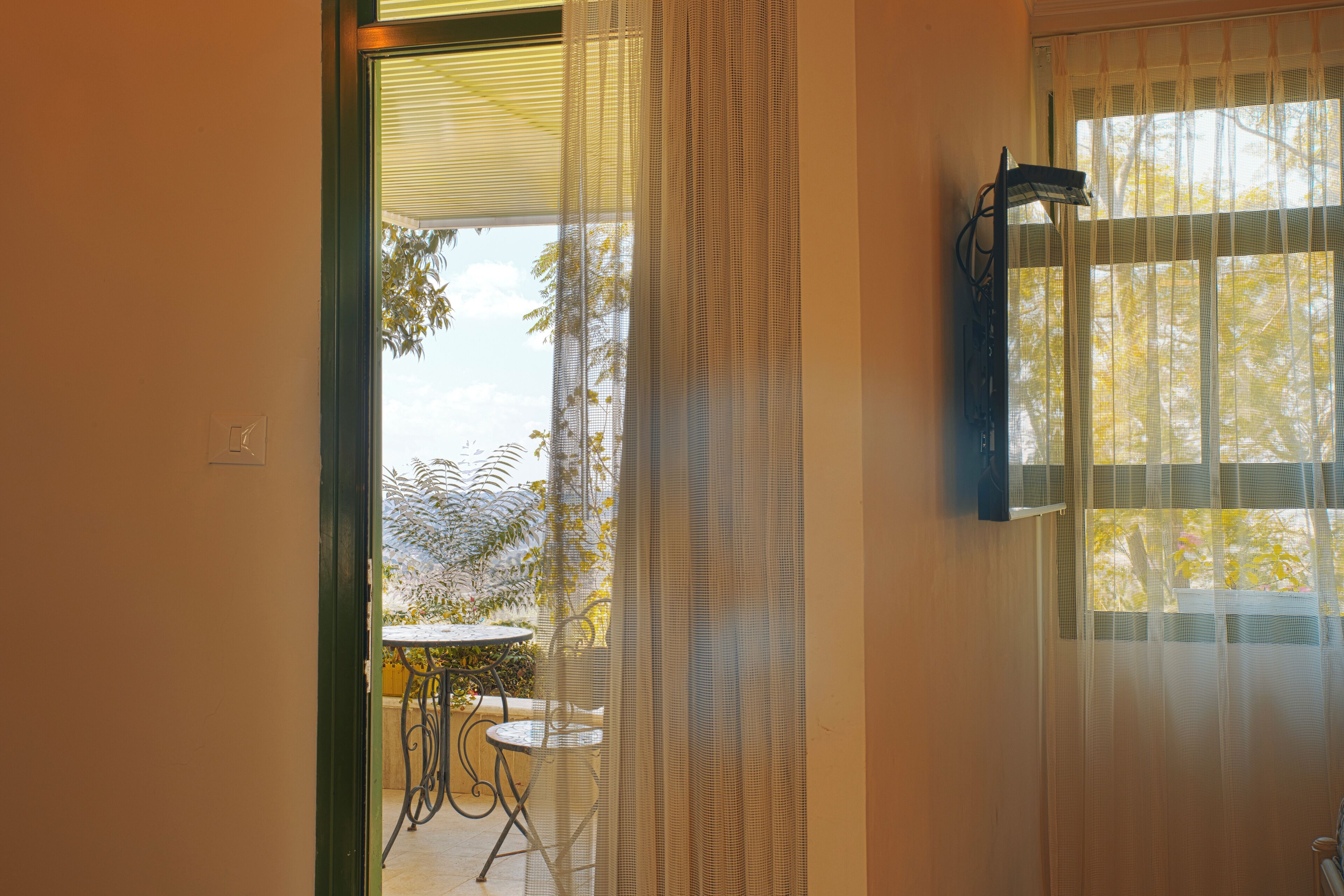 A room with a view of a patio area, a table, and chairs.